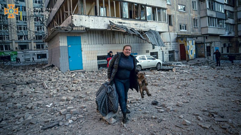 A woman carrying her dog evacuates from a residential building damaged by Russian shelling in Kyiv, Ukraine, March 16, 2022. (CNS photo/State Emergency Service of Ukraine handout via Reuters)