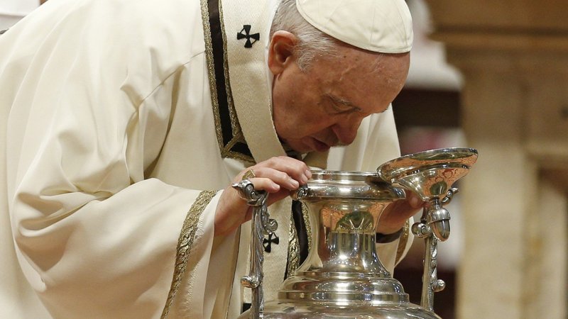 Pope Francis breathes on chrism oil, a gesture symbolizing the infusion of the Holy Spirit, as he celebrates Holy Thursday chrism Mass in St. Peter's Basilica at the Vatican April 14, 2022. (CNS photo/Paul Haring)
