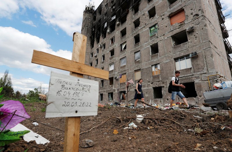 A grave of a civilian killed during Russian attacks on Mariupol, Ukraine, is seen next to a damaged apartment building April 28, 2022. (CNS photo/Alexander Ermochenko, Reuters)