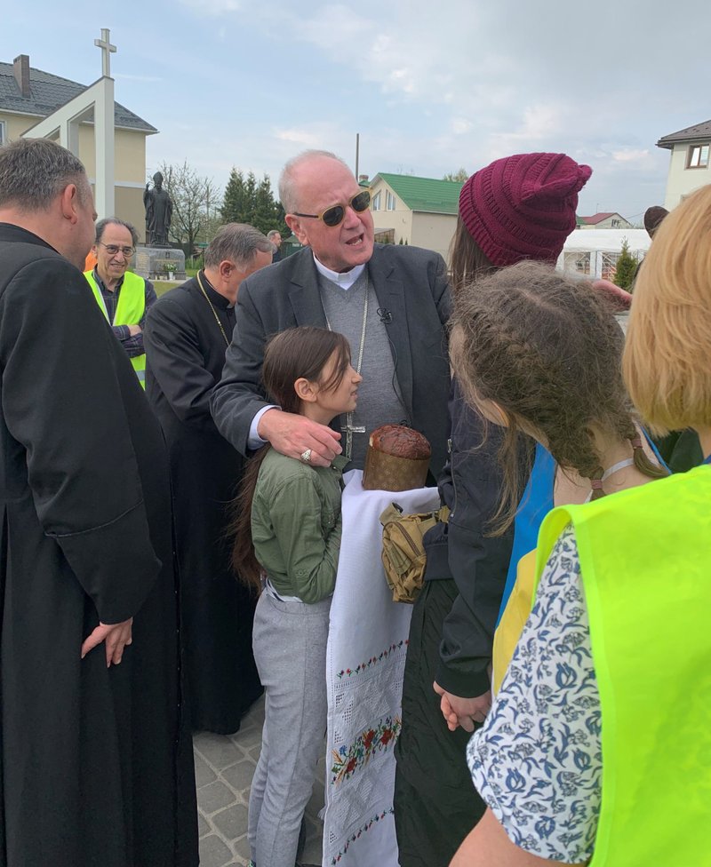 New York Cardinal Timothy M. Dolan, chairman of the Catholic Near East Welfare Association, embraces a girl who greeted him with bread and salt, a traditional way to greet and honor guests in Slavic cultures, during a visit to Lviv, Ukraine, May 2, 2022. (CNS photo/Michael la Civita, courtesy CNEWA)