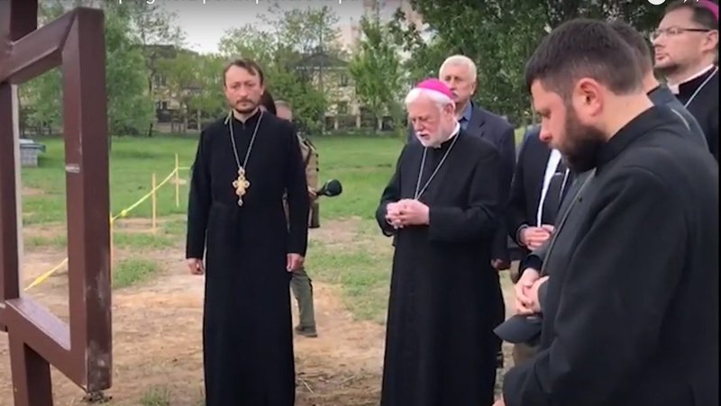 Archbishop Paul R. Gallagher, Vatican foreign minister, prays at the site of a mass grave near the Orthodox Church of St. Andrew in Bucha, Ukraine, May 20, 2022, in this still image taken from video posted by the Vatican. (CNS photo/Vatican Media)