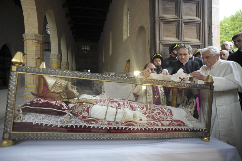 Pope Benedict XVI lays his pallium on the casket of St. Celestine V, a 13th-century pope who resigned, during a 2009 visit to the Basilica of Santa Maria di Collemaggio in L'Aquila, Italy, in this April 28, 2009, file photo. The Vatican announced June 4, 2022, that Pope Francis will visit LAquila Aug. 28 and will celebrate Mass in the square outside the basilica. (CNS photo/L'Osservatore Romano via Reuters)
