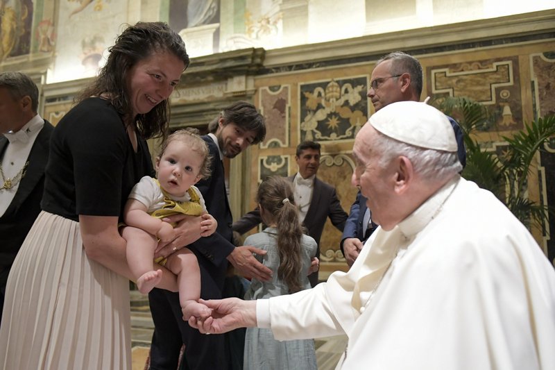 Pope touches the foot of a baby during an audience with members of the Federation of Catholic Family Associations in Europe at the Vatican June 10, 2022. (CNS photo/Vatican Media)