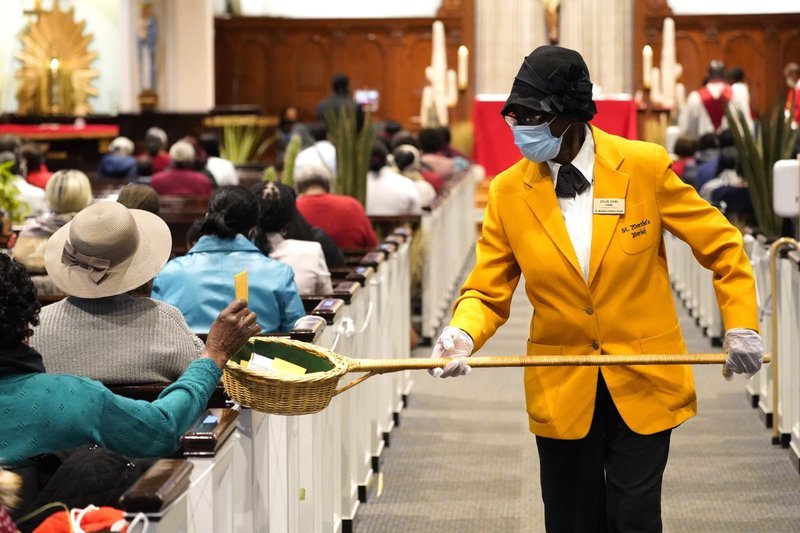 Usher Julie Noel is seen using a collection basket during Mass at St. Martha Catholic Church in Uniondale, N.Y., March 28, 2021. (CNS photo/Gregory A. Shemitz)