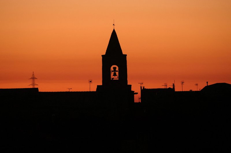 The bell tower of a church is seen during sunset in the village of Montmaneu, Spain, Jan. 28, 2022. (CNS photo/Nacho Doce, Reuters)