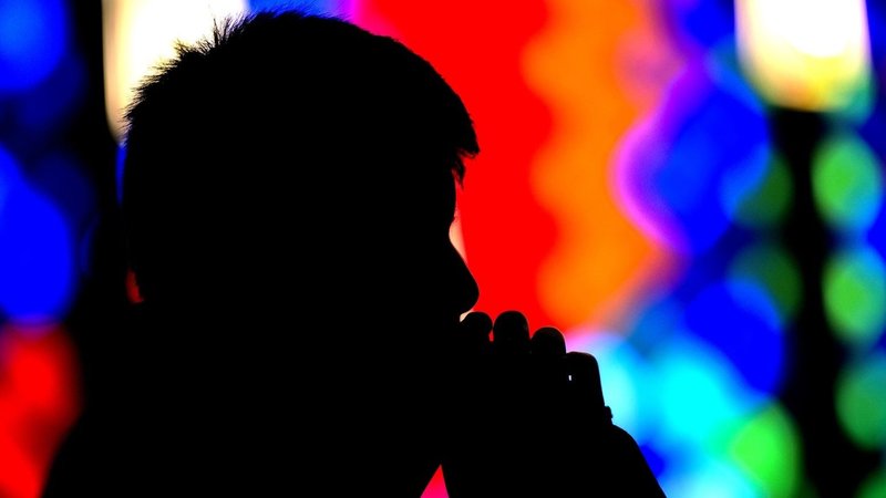 A teenager is silhouetted as he prays during Mass at St. John the Evangelist Church in Greece, N.Y., Nov. 23, 2014. (CNS photo/Mike Crupi, Catholic Courier)