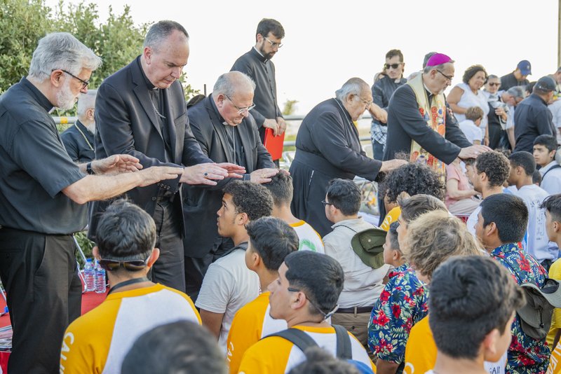 Auxiliary Bishop Timothy Freyer of Orange (second from left) and other bishops bless young men who felt the call to discern the priesthood at the July 19, 2022 vocational meeting of the Neocatechumenal Way in the U.S. at the Domus Galilaeae in Israel. At right, wearing a stole, is Archbishop Pierbattista Pizzaballa, who presided the event. (AEROJO Drone Productions)