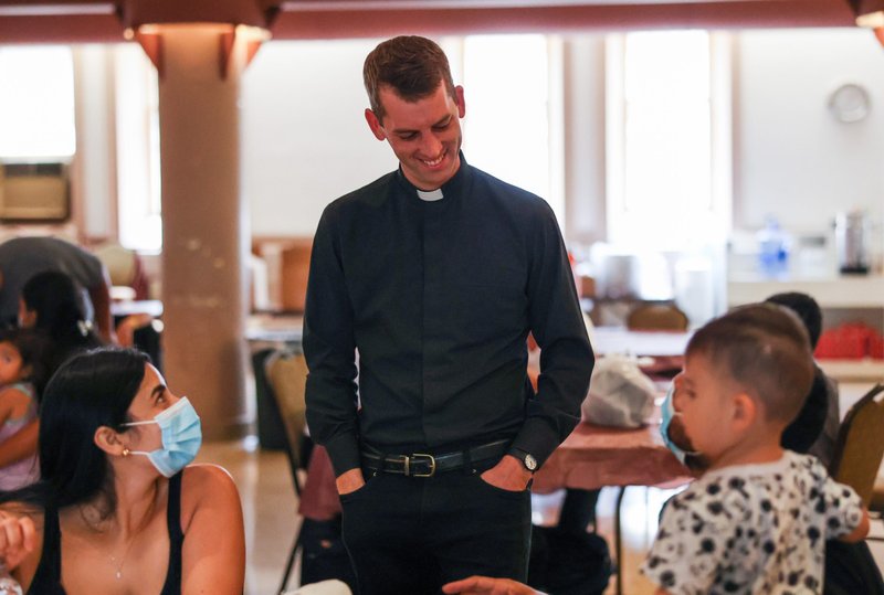 Father Brendan Glasgow, parochial vicar at St. Peter's Church on Capitol Hill in Washington, visits with migrants in the parish hall Aug. 5, 2022. Twenty-seven migrants arrived at the parish that afternoon following a two-day bus ride from Arizona. (CNS photo/Andrew Biraj, Catholic Standard)