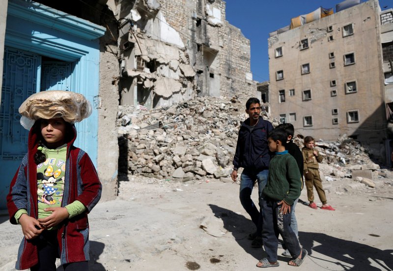 A girl carries a stack of pita bread on her head as she walks near rubble of damaged buildings in Aleppo, Syria, April 12, 2019. The Chaldean Catholic bishop of Aleppo said 11 years of war and the accompanying economic sanctions have left the city impoverished. (CNS photo/Omar Sanadiki, Reuters)
