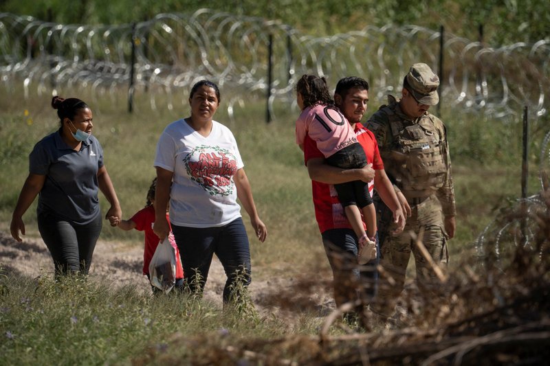 Migrants in Eagle Pass, Texas, walk with a U.S. National Guard officer after crossing the Rio Grande July 25, 2022. (CNS photo/Go Nakamura, Reuters)