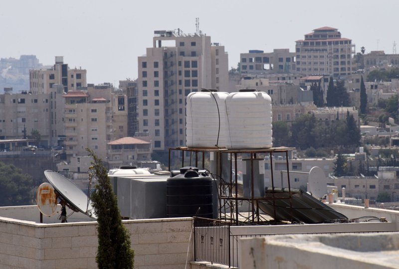 Black and white tanks, each capable of holding 1,500 liters of water, rest on top of Palestinian homes in Bethlehem, West Bank, Aug. 22, 2022. Israel has strict control of water sources for Palestinians. (CNS photo/Debbie Hill)