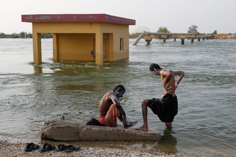 Men who were displaced by flooding bathe amid floodwaters in Sehwan, Pakistan, Sept.13, 2022. As of Sept. 15, Pakistan's disaster management office reported more than 1,500 people dead since half the country became submerged starting in June. (CNS photo/Akhtar Soomro, Reuters)