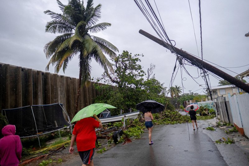 People in Penuelas, Puerto Rico, walk on a street affected by the passing of Hurricane Fiona Sept. 19, 2022. (CNS photo/Ricardo Arduengo, Reuters)