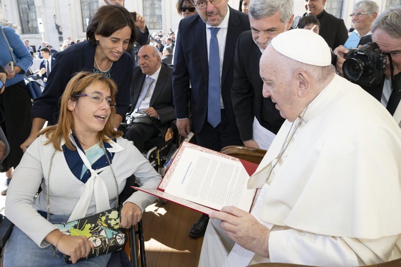 Pope Francis accepts a document on people with disabilities from Giulia Cirillo, a member of the Sant'Egidio community, at the end of the general audience in St. Peter's Square at the Vatican Sept. 21, 2022. People with disabilities submitted a draft document to the Synod of Bishops on the needs of people with disabilities and their contributions to the life of the church. (CNS photo/Vatican Media)