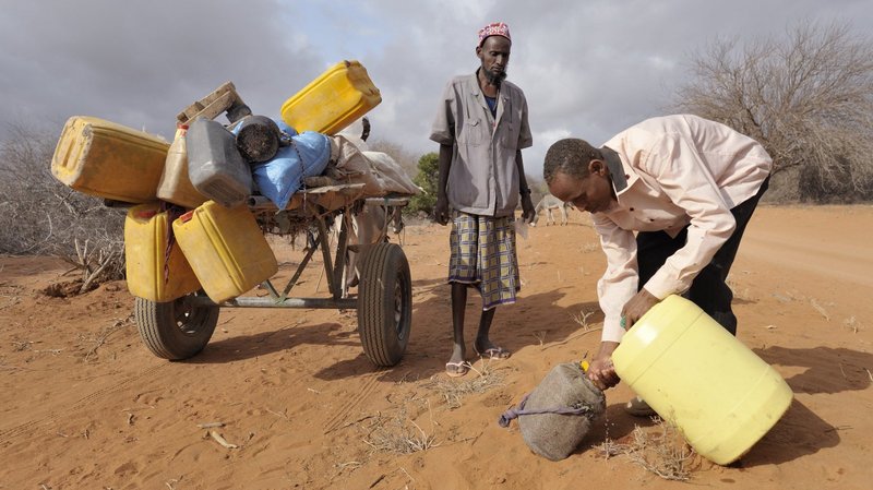 Adow Ibrahim Ali, right, is pictured in a file photo providing water to Ibrahim Osman Mohammed in a remote section of eastern Kenya near the Somali border. Traveling with his cousin, Mohammed left his home in Buale, Somalia, three weeks earlier because severe drought killed most of their animals. (CNS photo/Paul Jeffrey)