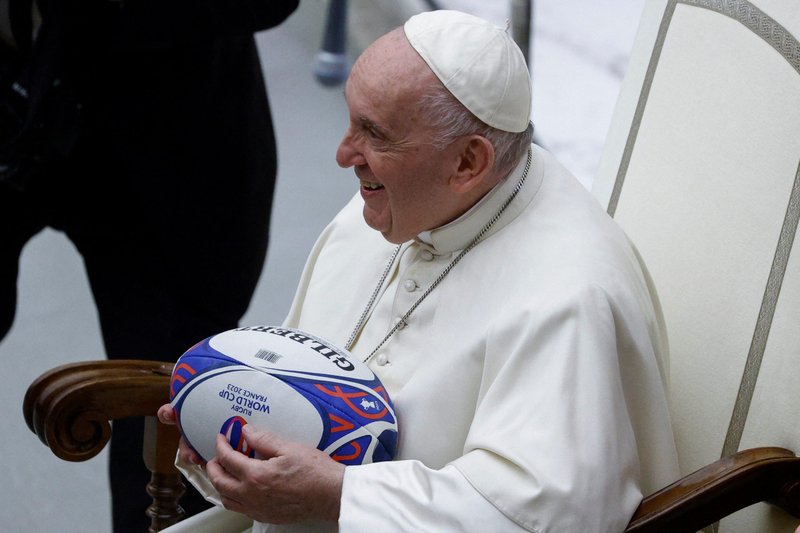 Pope Francis smiles after being presented with a rugby ball at the "Sport for All" summit in the Vatican audience hall Sept. 30, 2022. (CNS photo/Guglielmo Mangiapane, Reuters)