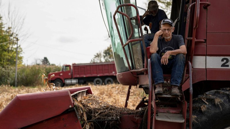 Dale Nething, 86, of Ravenna, Ohio, waits on the steps of his combine Oct. 11, 2021, as his son Don Nething, 62, troubleshoots the harvester after it breaks down. (CNS photo/Dane Rhys, Reuters)