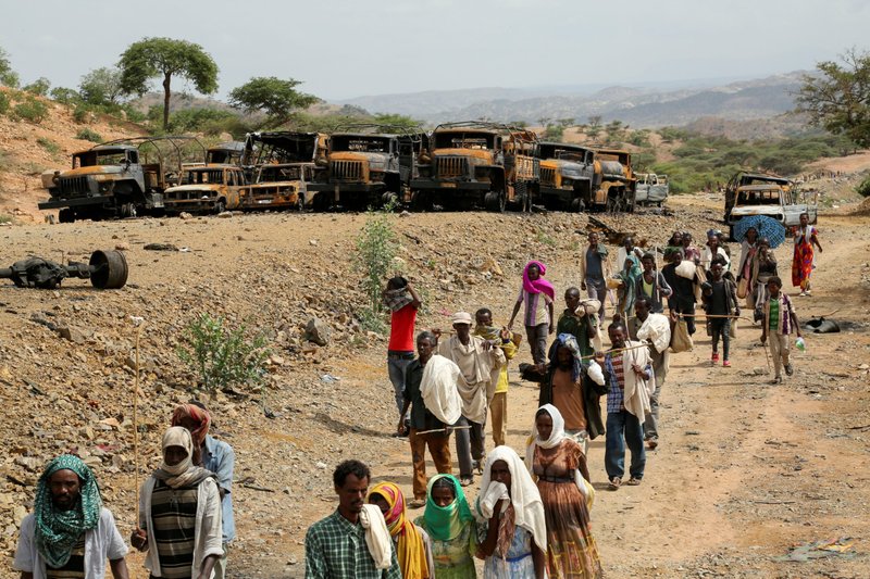 Villagers returning from a market in the town of Yechila walk past scores of burned vehicles in Ethiopia's Tigray region July 10, 2021. Bishop Tesfasellassie Medhin of Adigrat restated his call for the local and international community to act to save millions of people trapped in war. (CNS photo/Giulia Paravicini, Reuters)