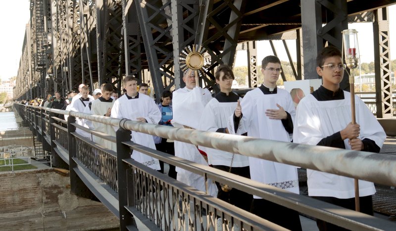 Bishop Thomas R. Zinkula of Davenport, Iowa, carries the monstrance with the Eucharist over the Mississippi River on Government (Arsenal) Bridge from Davenport to Rock Island, Ill., Oct. 8, 2022, during a bistate eucharistic procession. (CNS photo/Jennifer Willems, The Catholic Post)