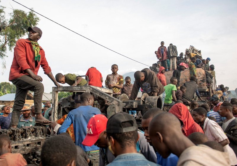 People climb atop a destroyed U.N. peacekeeping truck in Kanyarutshinya, Congo, Nov. 2, 2022. The truck was part of a convoy that was attacked when it stopped at an army checkpoint near an internally displaced persons camp. (CNS photo/Arlette Bashizi, Reuters)