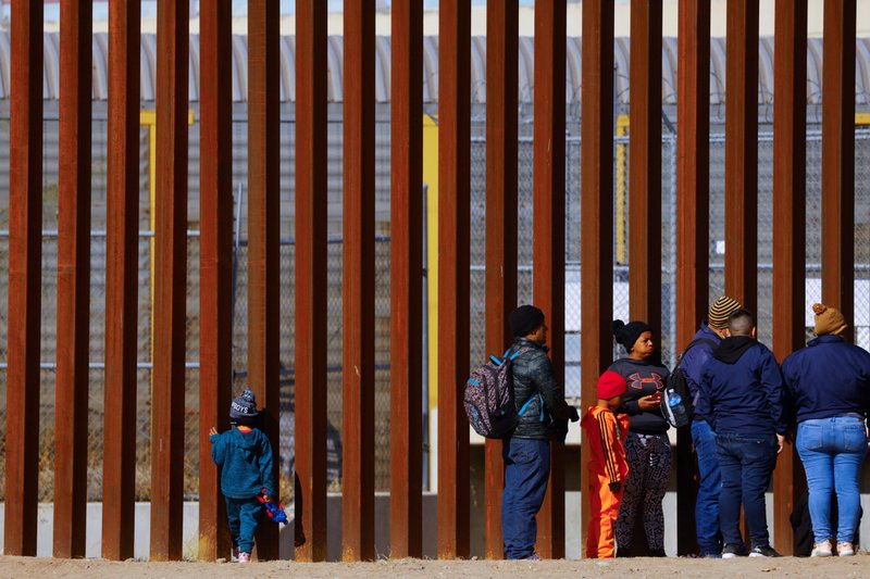 George, 5, a migrant boy from Venezuela traveling with his family, looks through the border wall as family members line up to request asylum in El Paso, Texas, Dec. 27, 2022. (CNS photo/Jose Luis Gonzalez, Reuters)