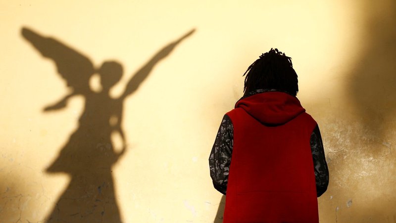 A person prays near a shadow of a sculpture depicting an angel outside Holy Trinity Cathedral in Addis Ababa, Ethiopia in 2017. (CNS/Tiksa Negeri, Reuters)
