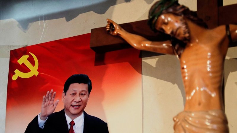 A poster of Chinese President Xi Jinping hangs next to a crucifix on the wall of the house of a Tibetan Catholic in China's Yunnan province in 2018. (CNS/Tyrone Siu, Reuters)