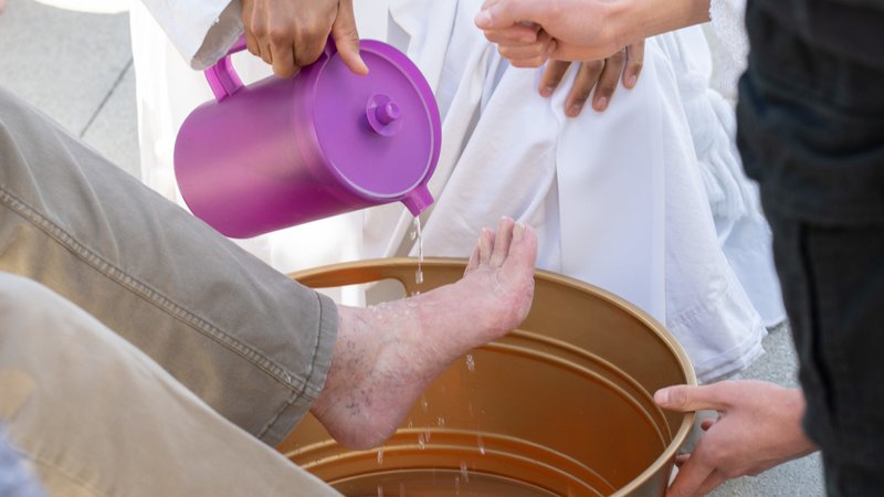 Father Claude Williams, the pastor at Sts. Peter and Paul Church, washes the feet of a child during a public Holy Thursday event at Wilmington Town Square Park on April 6. (Carson VanVooren)