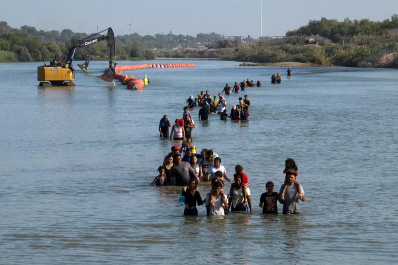 Migrants wade past buoys July 27, 2023, that were constructed to deter migrants attempting to cross the Rio Grande from Mexico into Eagle Pass, Texas. A federal judge ordered Texas Sept. 6 to remove the floating barriers and prohibited the state from adding or reinstalling additional buoys. (OSV News/Adrees Latif, Reuters)