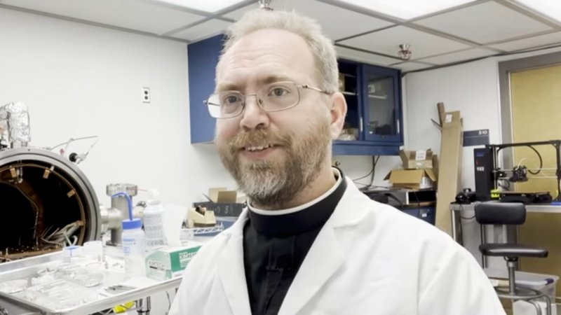 Jesuit Brother Robert Macke presents a device to study the porosity and density of specimens retrieved from the asteroid Bennu by the Osiris-Rex space mission at the Lunar and Planetary Laboratory in Tucson as seen in a YouTube video he posted on his channel Aug 12, 2022. (CNS/YouTube video screenshot)