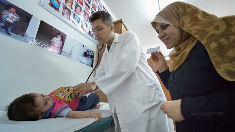 As the mother attempts distraction, Dr. Mohi El Sharqawi examines a child in the pediatric department at the CNEWA-supported al-Ahli Arab Hospital in Gaza City in 2015. Gaza Health Ministry said at least 500 people were killed Oct. 17, 2023, in the rocket on the hospital. (OSV News photo/Paul Jeffrey)