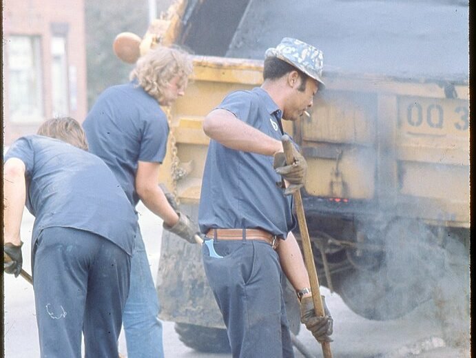 “Construction Workers Spreading Asphalt.” (Wikimedia Commons)