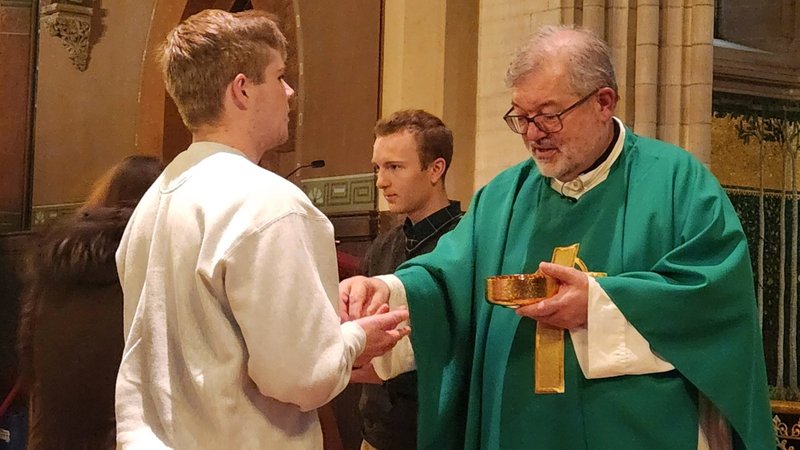Father Daniel McMullin distributes Communion during a Nov. 5, 2023, Mass at Cornell University's Sage Chapel in Ithaca, N.Y. During the Mass, Father McMullin praised students for "the kindness they have shown one another, especially to our Jewish and Muslim friends," following online posts threatening extreme violence against Jews on campus since the start of the Israel-Hamas war Oct. 7. (OSV News/Mike Latona, Catholic Courier)