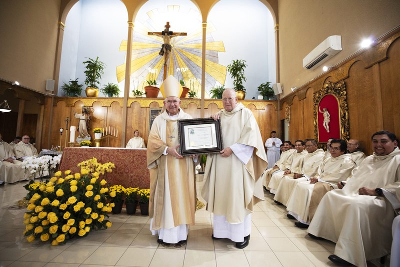 Los Angeles Archbishop José H. Gomez presents a certificate to Msgr. John Moretta, the pastor at Resurrection Church in Boyle Heights, during the parish’s centennial Mass on Oct. 15. (Victor Alemán)