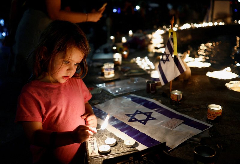 A girl lights a candle as people gather for a vigil in Tel Aviv, Israel, Nov. 7, to mark the one-month anniversary of the deadly attack by Palestinian Islamist group Hamas on Israel. (OSV News/Evelyn Hockstein, Reuters)