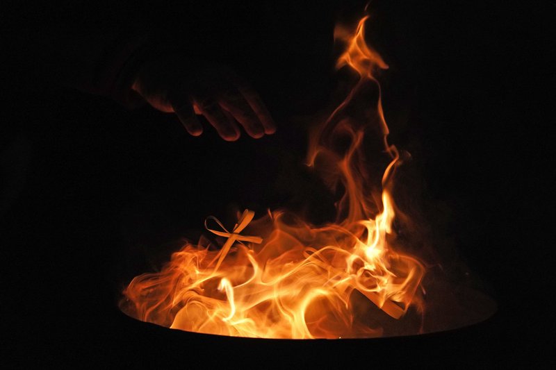Dried palms are placed in a fire at the conclusion of a Mardi Gras evening prayer service. Ashes from the fire are used on Ash Wednesday. (CNS/Gregory A. Shemitz)