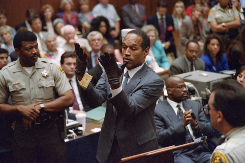 O.J. Simpson looks at a new pair of gloves, the same type found at the murder scene, which prosecutors had him put on for the jury on June 21, 1995, during the double murder trial in Los Angeles. (Vince Bucci/AFP via Getty Images)