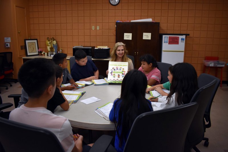 Susie Lopez, a facilitator of the VIRTUS safety program, shows off to students the new poster created for the 2024 Abuse Prevention Month in April. (Submitted photo)