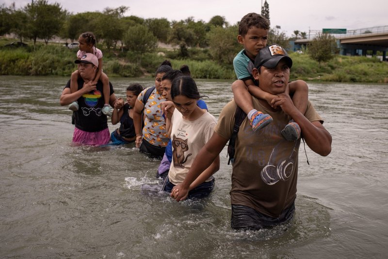 Orlando, a migrant from Ecuador, carries 4-year-old Peter as they wade through the Rio Grande from Mexico into Eagle Pass, Texas, Oct. 6, 2023. (OSV News/Adrees Latif, Reuters)