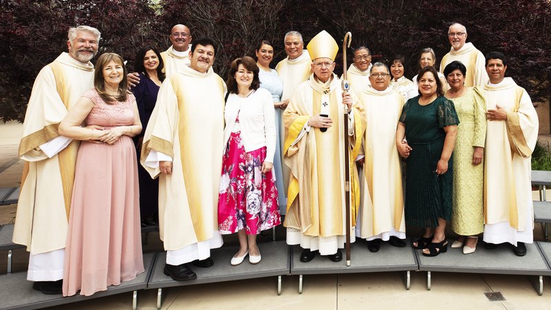 The eight deacons and their wives pose with Archbishop José H. Gomez following their ordination Mass. (Victor Alemán)