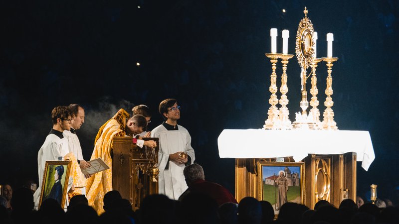 Bishop Andrew H. Cozzens kneels in prayer before the monstrance during Eucharistic adoration at the opening revival session of the National Eucharistic Congress at Lucas Oil Stadium in Indianapolis July 17. The altar was adorned with the saint icons that were carried by the perpetual pilgrims of the two-month national pilgrimage. (OSV News/Bob Roller)