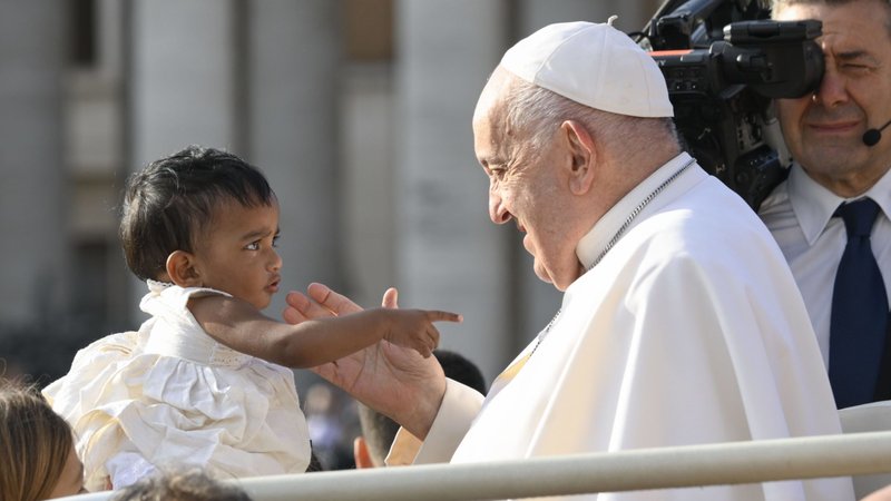 Pope Francis greets a young child as he rides in the popemobile around St. Peter's Square at the Vatican before his weekly general audience Sept. 18, 2024. (CNS photo/Vatican Media)