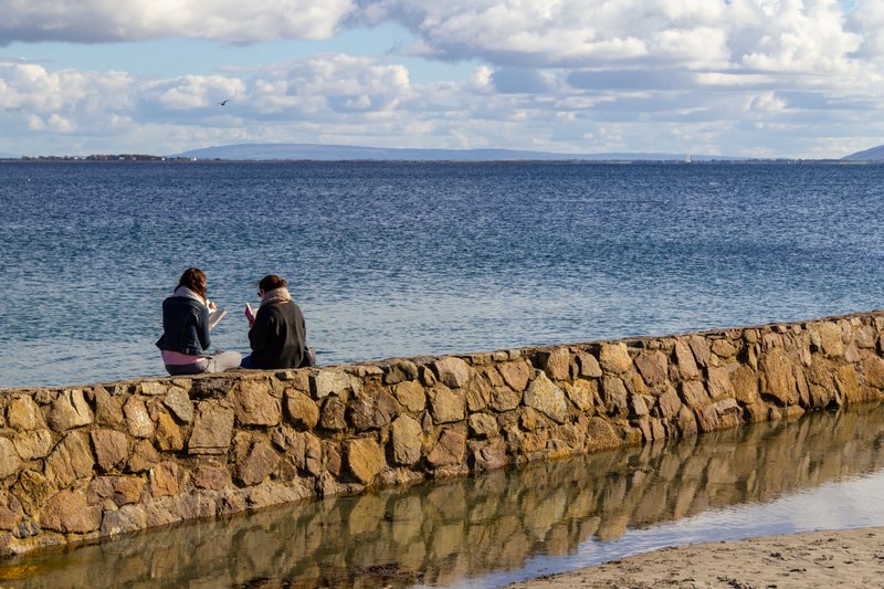 Two women read on Blackrock Beach in Salthill, Galway, Ireland. (Shutterstock)