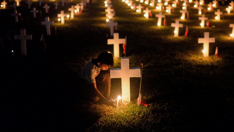 A Scout lights candles on All Saints’ Day Nov. 1, 2019, during a tribute for departed soldiers at a cemetery in Taguig, Philippines. (CNS/Eloisa Lopez, Reuters)