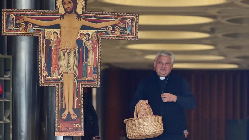 Cardinal Konrad Krajewski, prefect of the Vatican's Dicastery for the Service of Charity and papal almoner, stands with a basket at the entrance of the Paul VI Hall in Vatican City, where Synod on Synodality delegates meet, to collect alms on Oct. 7, 2024, the first anniversary of Hamas' attack on Israel and subsequent Israel-Hamas war. That same night the funds were received by Vatican's embassy in Jerusalem and were transferred to the Holy Family Parish in Gaza City. (OSV News photo/courtesy Dicastery for the Service of Charity)