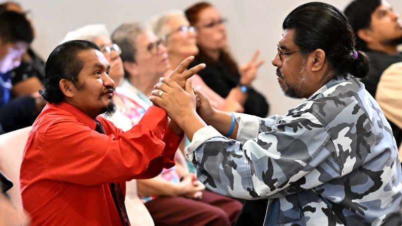 A deaf man follows the hand signals of an interpreter during Mass at Holy Angels Catholic Church of the Deaf in Vernon. (John McCoy)
