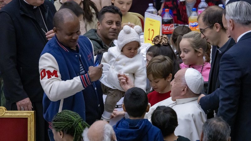 Pope Francis greets a man and child during a lunch in the Vatican audience hall Nov. 17, 2024, the World Day of the Poor. (CNS photo/Pablo Esparza)