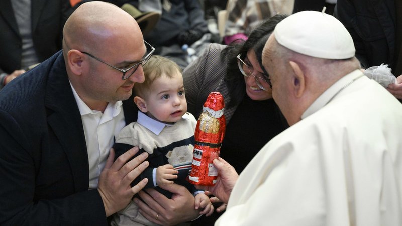 Pope Francis gives a child a large chocolate Santa after his weekly general audience in the Paul VI Audience Hall at the Vatican Dec. 18, 2024. (CNS photo/Vatican Media)