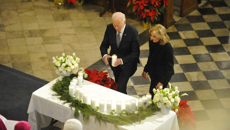 At an interfaith prayer service Jan. 6, 2025, at St. Louis Cathedral in New Orleans, President Joe Biden, with first lady Jill Biden, places a candle in a semicircle atop a table set up in front of the altar in memory of the 14 people killed during New Year's celebrations in the city's famed French Quarter early Jan. 1. (OSV News photo/Peter Finney Jr., Clarion Herald)