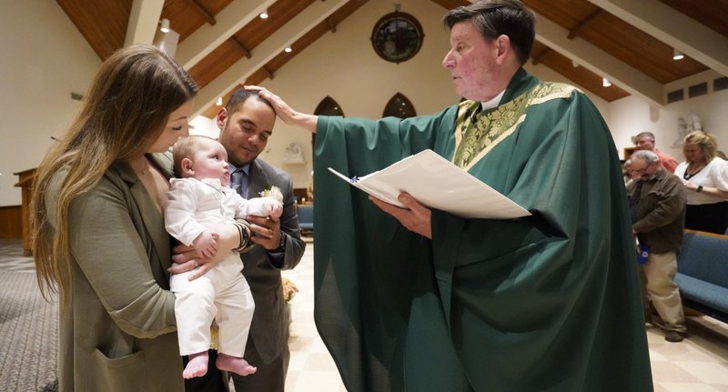 Christina and Julio Prendergast hold their 5-month-old son, Gabriel James, as the couple receives a blessing from Msgr. Frank Schneider during the baby's baptismal ceremony Nov. 12, 2022, at St. John the Baptist Church in Wading River, N.Y. Bishop Michael F. Burbidge of Arlington, Va., issued a pastoral letter Jan. 22, 2025, highlighting "the threats posed by IVF to human dignity and human rights," while calling for greater compassion and accompaniment for couples experiencing infertility. (OSV News photo/CNS photo, Gregory A. Shemitz)